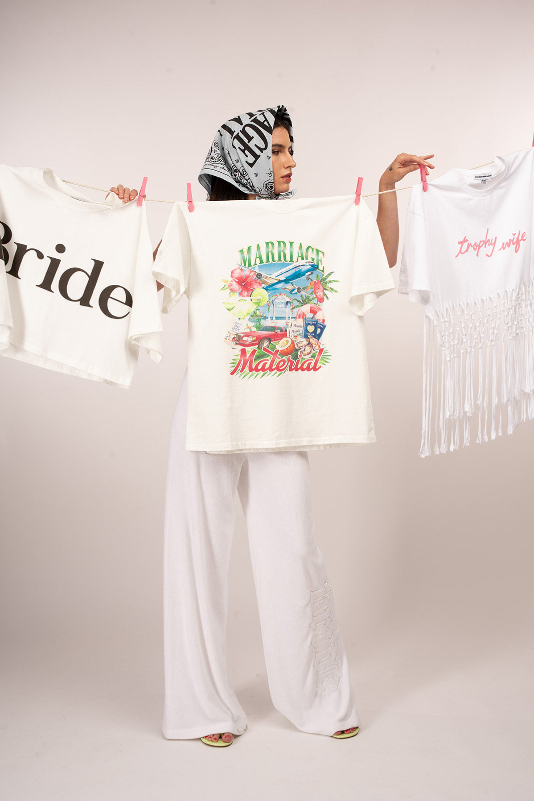 Woman holding t-shirts with text and graphics on a plain background