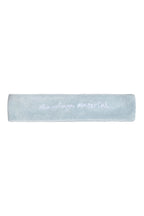 Flat lay of white terry cloth headband with 'Marriage Material™' embroidery