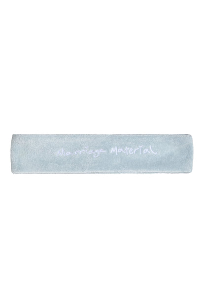 Flat lay of white terry cloth headband with 'Marriage Material™' embroidery