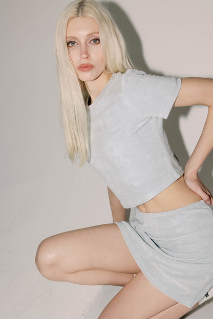 Model wearing blue terry midi skirt with "Marriage Material™" graphic near hem, close-up pose