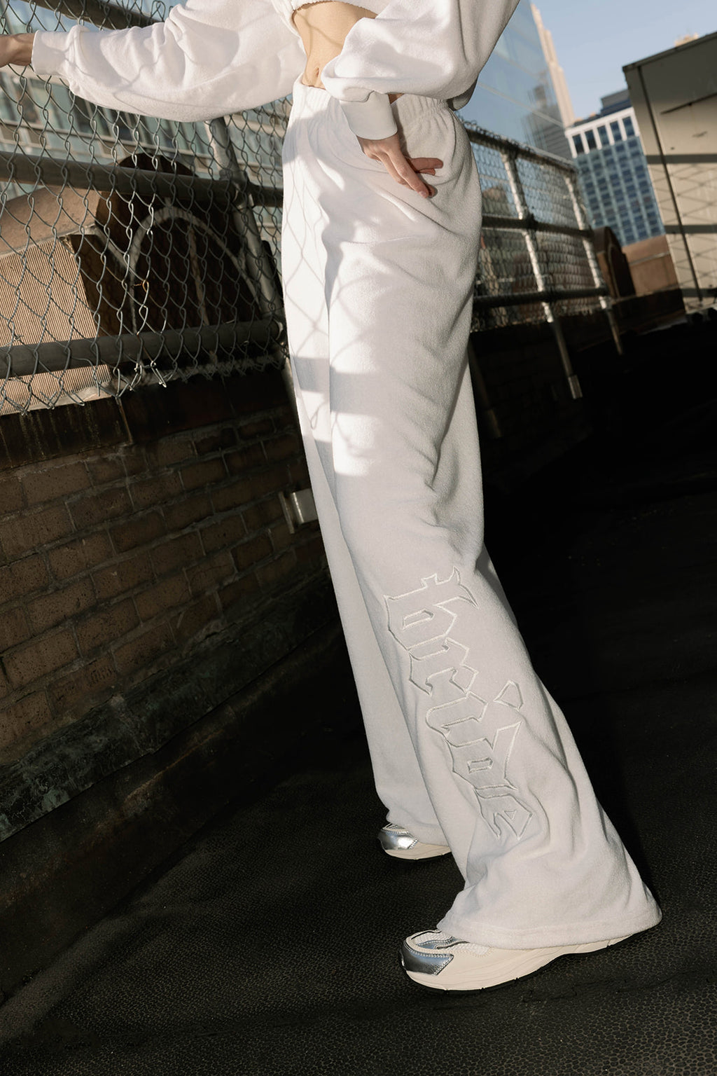 Detail view of 'Bride' text on white terry pants, styled on model
