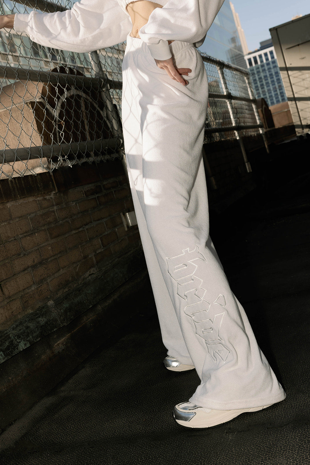 Detail view of 'Bride' text on white terry pants, styled on model