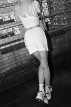 Model facing away wearing white terry skirt featuring bold 'BRIDE' lettering on the back